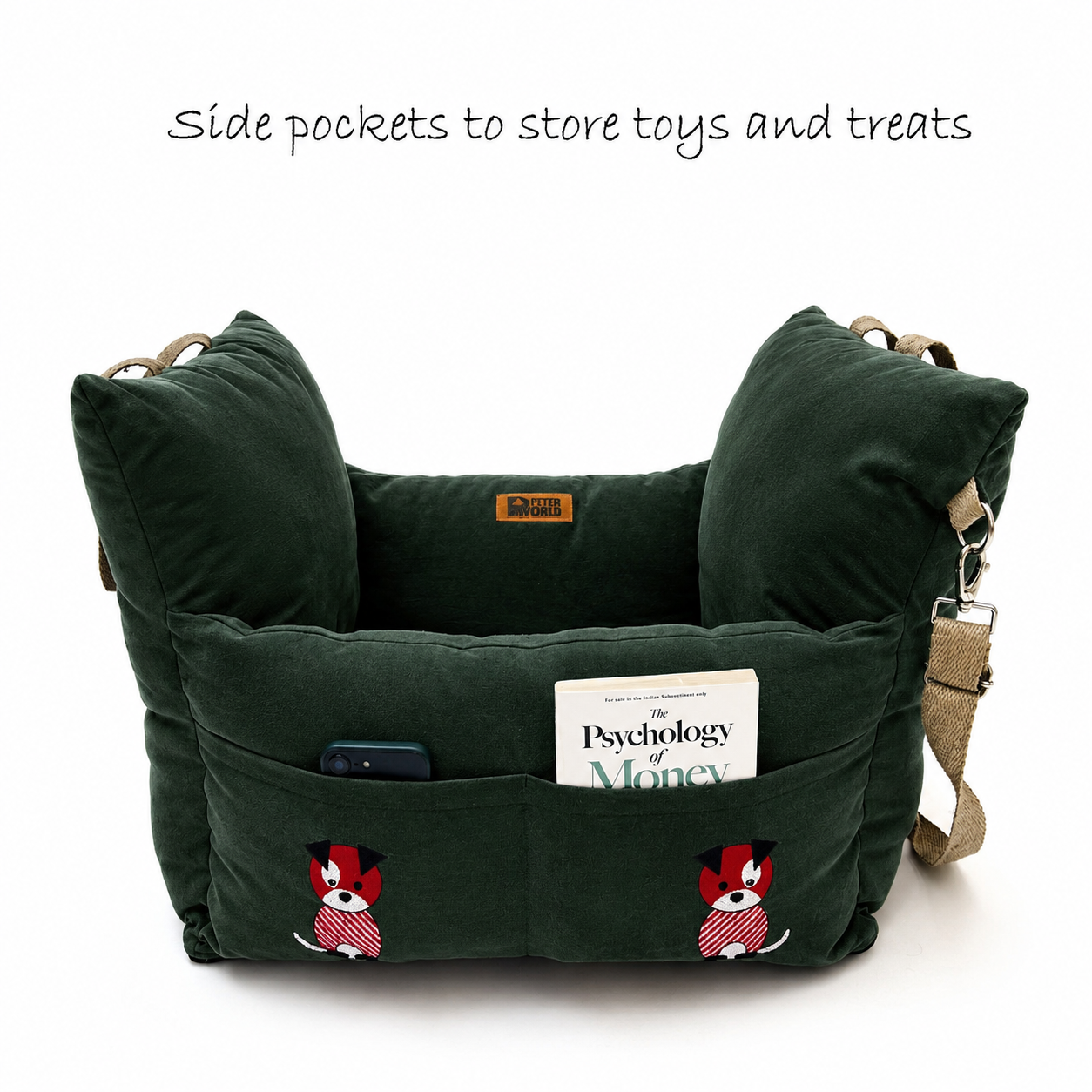 A dark olive green padded dog travel bed with side pockets holding a phone and a magazine, featuring embroidered cartoon puppies on the front pockets and a tan adjustable shoulder strap, shown on a white background with text reading 'Side pockets to store toys and treats'.