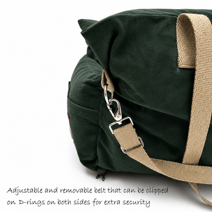 Dark green canvas dog travel bed with beige webbing straps and silver metal clips, shown on a white background with text describing the adjustable and removable belt.